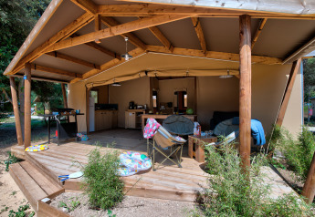 Safari tent Blokhut Cotton Comfort with a covered wooden deck, outdoor furniture, and open kitchen area.