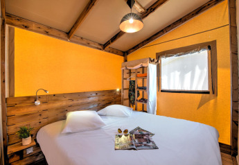 Soveværelse i Blokhut Cotton Comfort safaritelte på Flower Camping Le Bel Air med træmøbler og dobbeltseng.