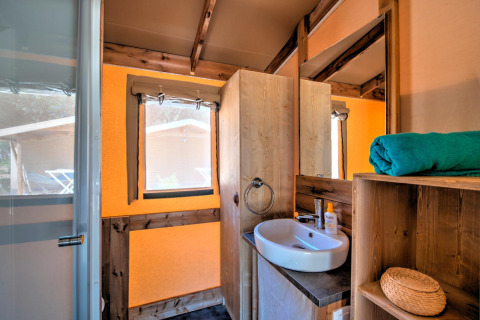 Badkamer van safaritent Blokhut Cotton Comfort op Flower Camping Le Bel Air in Frankrijk, met wasbak en handdoek.