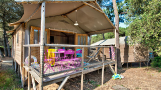 Vue extérieure de la cabane Hut Lodge hout Comfort, avec chaises colorées et jouets pour enfants sur la terrasse