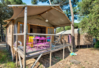 Outdoor view of Hut Lodge hout Comfort cabin, with colorful chairs and children's toys on the wooden deck