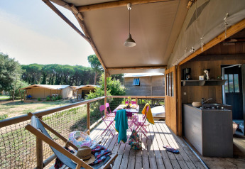 Udsigt fra verandaen af en hyggelig hytte på Flower Camping Le Bel Air i Frankrig med udendørs spiseplads.