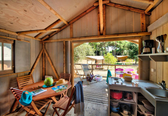 Vue intérieure de la Hut Lodge hout Comfort au Flower Camping Le Bel Air avec terrasse et vue sur la forêt.
