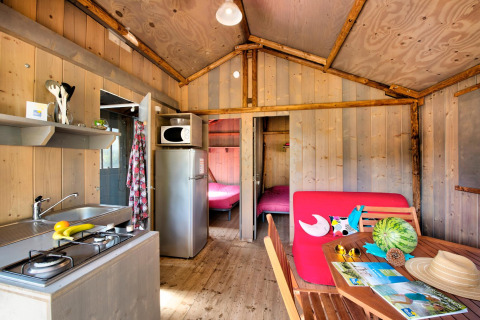 Interiør af Hut Lodge hout Comfort, Flower Camping Le Bel Air, Frankrig, med køkken og spiseområde.