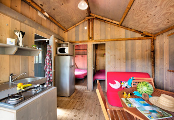 Interiør af Hut Lodge hout Comfort, Flower Camping Le Bel Air, Frankrig, med køkken og spiseområde.