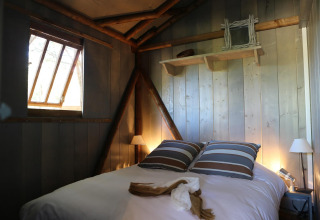 Gemütliches Schlafzimmer in einer Holzhütte bei Hut Lodge hout Comfort, Flower Camping Le Bel Air, Frankreich.