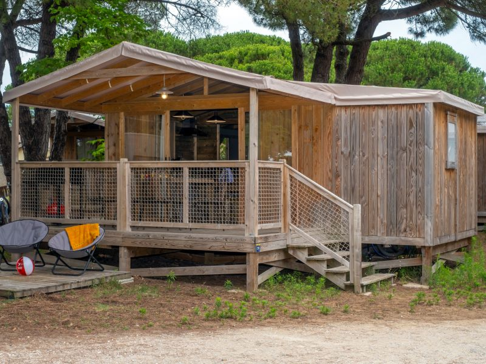 Cosyflower Premium houten chalet met veranda bij Flower Camping Le Bel Air in Frankrijk, omringd door bomen.