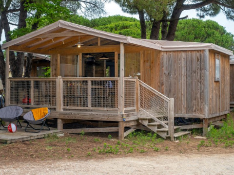 Cosyflower Premium houten hut met terras bij Flower Camping Le Bel Air in Frankrijk, tussen het groen.