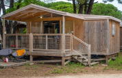 Cosyflower Premium houten hut met terras bij Flower Camping Le Bel Air in Frankrijk, tussen het groen.