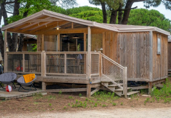Træhytte Cosyflower Premium med terrasse på Flower Camping Le Bel Air i Frankrig, omgivet af træer.