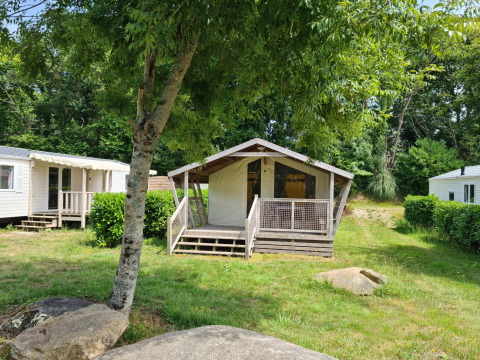 Tente safari Freeflower Standard au Flower Camping Le Kerleyou en France, entourée de verdure et de chalets.