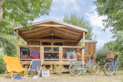Cosyflower Premium houten chalet met overdekt terras, ligstoelen, fietsen en zomerse attributen buiten.