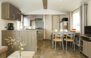 Moderne hutkeuken en eetruimte met houtafwerking, veel licht, koffiezetapparaat en tafel voor vier.