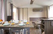 Moderne hutinterieur met ontbijttafel, zithoek en kleurrijke gestreepte gordijnen aan ramen.