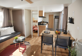 Moderne stue og køkken i Homeflower Premium-hytten med spisebord, sofa og naturligt lys.