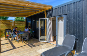Buitenterras bij Homeflower Premium, Flower Camping Le Kerleyou, Frankrijk, met mensen aan tafel.