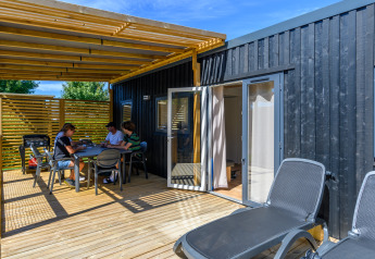 Udendørs terrasse ved Homeflower Premium, Flower Camping Le Kerleyou, med folk, borde og liggestole.