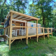 Udendørsbillede af Standaard Houten Stacaravan mobilhome med overdækket terrasse i skovområde.