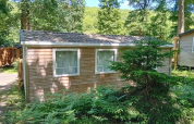Standard wooden mobile home at Flower Camping La Chênaie in France, surrounded by trees and greenery.