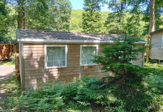 Mobil-home standard en bois à Flower Camping La Chênaie en France, entouré de verdure et d’arbres.