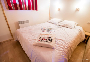 Dormitorio acogedor con cama doble, ropa de cama blanca y almohada de recuerdo en Chalet Bois Comfort, La Chênaie.