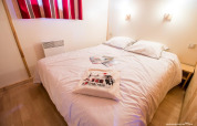 Cozy bedroom with double bed, white bedding, and souvenir pillow at Chalet Bois Comfort, La Chênaie, France.