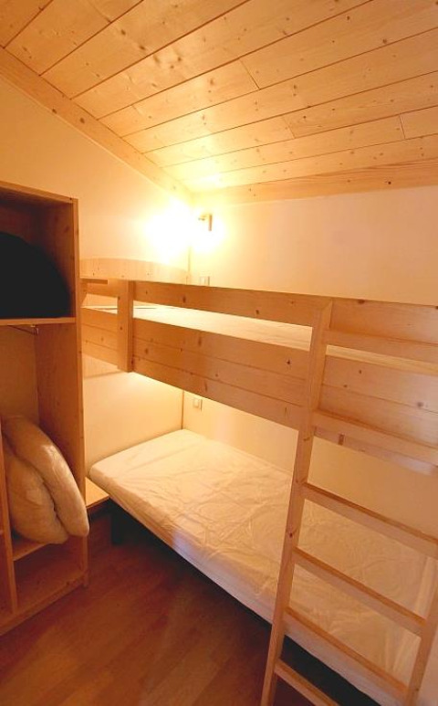 Gemütliches Zimmer mit Etagenbett und Holzdecke im Chalet Bois Comfort bei Flower Camping La Chênaie, Frankreich.