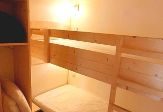Gemütliches Zimmer mit Etagenbett und Holzdecke im Chalet Bois Comfort bei Flower Camping La Chênaie, Frankreich.