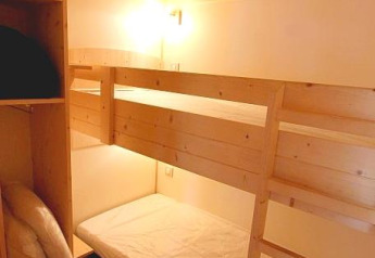 Chambre chaleureuse avec lits superposés et plafond bois au Chalet Bois Comfort, Flower Camping La Chênaie, France.