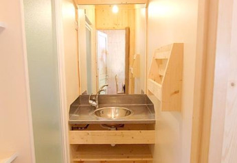 Baño estrecho con techo de madera y lavabo moderno en Chalet Bois Comfort de Flower Camping La Chênaie.