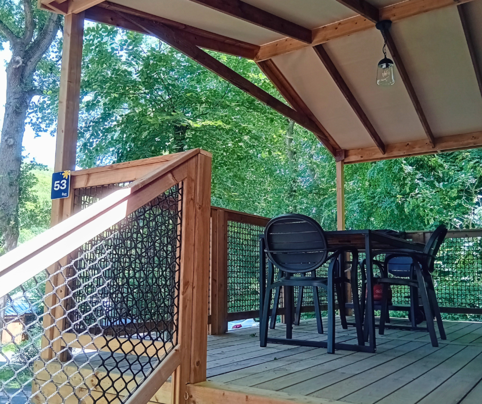 Overdekt houten terras met tafel en stoelen bij Cosyflower Premium, Flower Camping La Chênaie, Frankrijk.