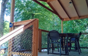 Covered wooden deck with table and chairs at Cosyflower Premium lodge, Flower Camping La Chênaie, France.