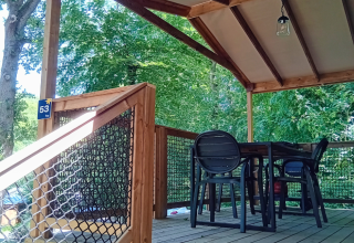 Überdachte Holzterrasse mit Sitzgruppe in der Cosyflower Premium Lodge, Flower Camping La Chênaie, Frankreich.