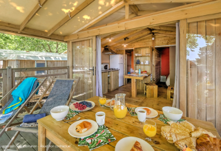 Frühstück auf der Terrasse einer gemütlichen Holzhütte mit moderner Einrichtung im Flower Camping La Chênaie, Frankreich.