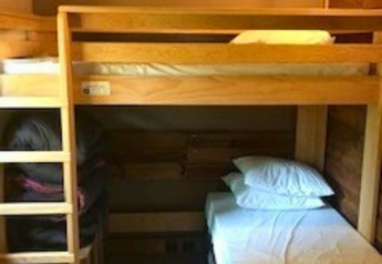 Letto a castello in legno in una stanza accogliente con soffitto spiovente presso Flower Camping La Chênaie, Francia.