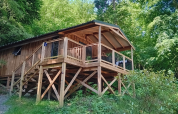 Luxuriöse Holz-Lodge mit Terrasse auf Stelzen im Flower Camping La Chênaie, umgeben von französischem Wald.