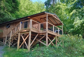 Lodge de madera elevada con terraza en Flower Camping La Chênaie, rodeada de bosque en Francia.