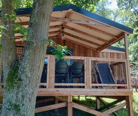 View of Lodge VIP Premium at Flower Camping La Chênaie in France, surrounded by lush trees and greenery.