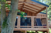 Blick auf die Lodge VIP Premium im Flower Camping La Chênaie in Frankreich, umgeben von grüner Natur.