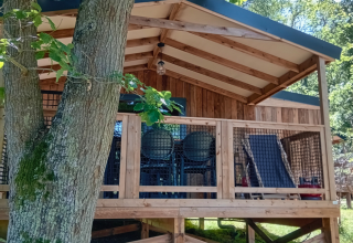 View of Lodge VIP Premium at Flower Camping La Chênaie in France, surrounded by lush trees and greenery.