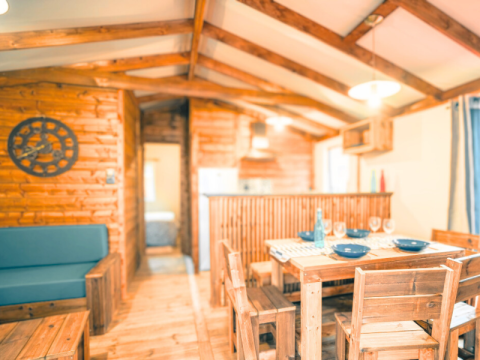 Interior of Lodge VIP Premium at Flower Camping La Chênaie in France, featuring wooden furniture and cozy layout.