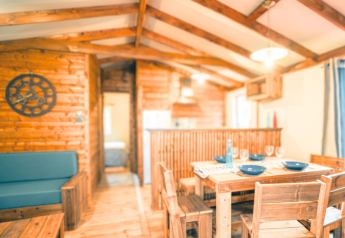 Interior del Lodge VIP Premium en Flower Camping La Chênaie, Francia, con muebles de madera y ambiente acogedor.