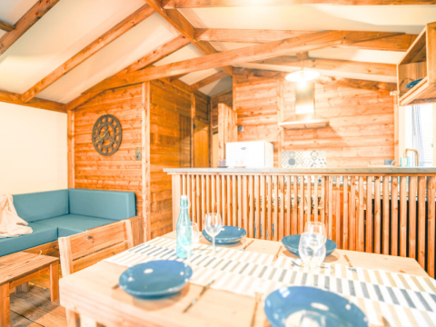 Interior of Lodge VIP Premium at Flower Camping La Chênaie in France, featuring wooden furniture and a dining area.