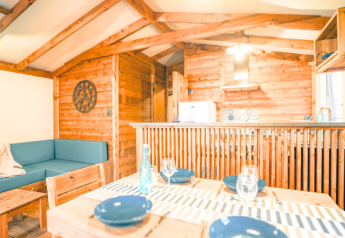 Interior de la Lodge VIP Premium en Flower Camping La Chênaie en Francia, con muebles de madera y comedor.