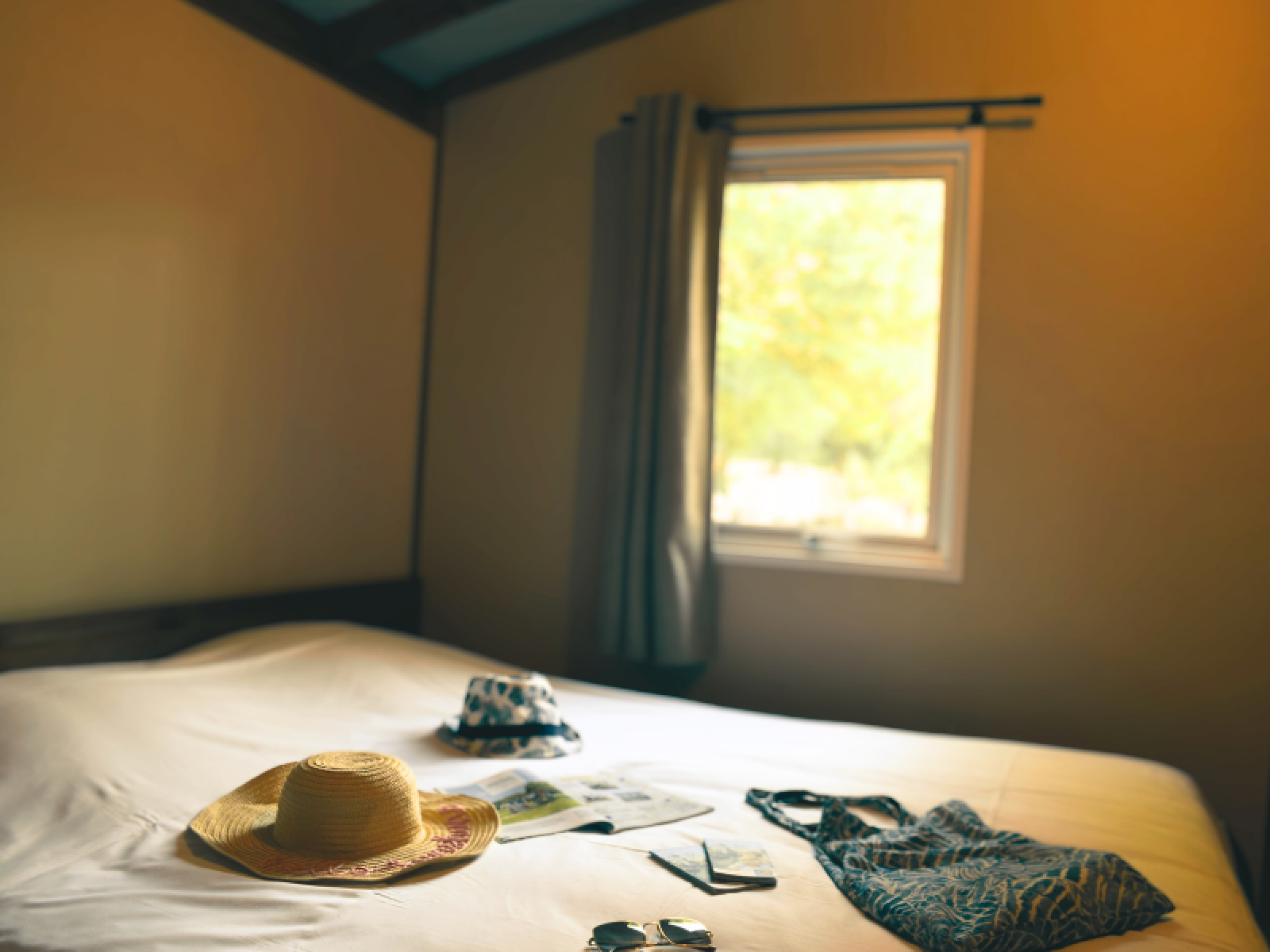 Sfeervolle kamer in Lodge VIP Premium, Flower Camping La Chênaie, Frankrijk, met accessoires op het bed.