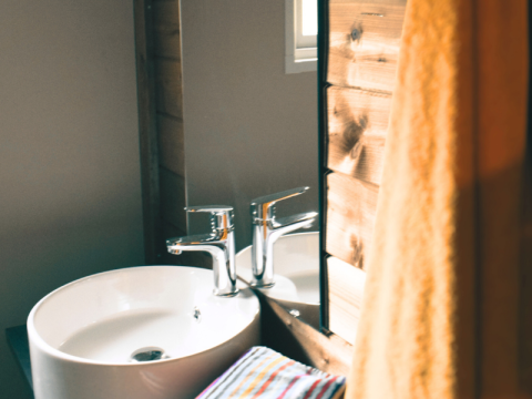 Modern sink and fixtures at Lodge VIP Premium at Flower Camping La Chênaie, France, with wooden accents and towel.