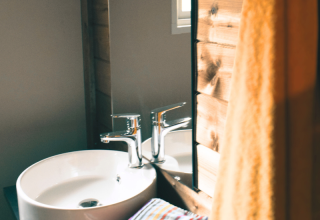 Modern sink and fixtures at Lodge VIP Premium at Flower Camping La Chênaie, France, with wooden accents and towel.