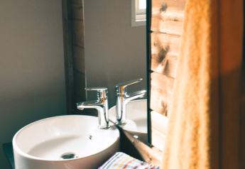 Modern sink and fixtures at Lodge VIP Premium at Flower Camping La Chênaie, France, with wooden accents and towel.