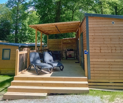 Houten lodge met overdekt terras en ligstoelen bij Homeflower Premium, Flower Camping La Chênaie in Frankrijk.