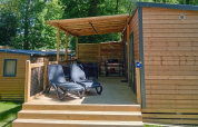 Houten lodge met overdekt terras en ligstoelen bij Homeflower Premium, Flower Camping La Chênaie, Frankrijk.